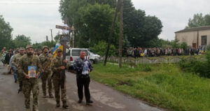 Процесія похорон. На чолі 
 колони військові .несуть хрест та портрет Сергія