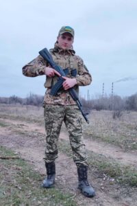 Кирило у повний зріст із автоматом
