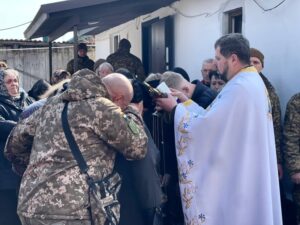 Рідні схилили голови перед святою книгою, яку читає батюшка