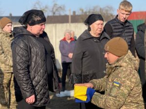 Військовий вручає прапор України Матері полеглого Геннадія