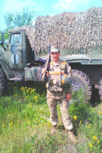 Іван у військовому спорядженні біля вантажівки