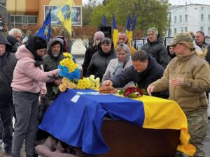 Хвилини прощання. На домовину обвиту прапором кладуть квіти