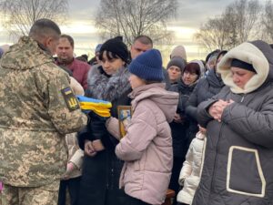 Військовий передає родині полеглого прапор