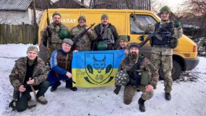 Бійці на фоні машини з прапором 