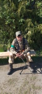 Стомлений. Відпочиває на лавці під хвойним деревом
