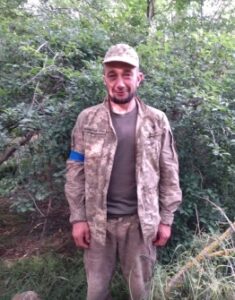 На фоні хвойного дерева у війсбькрвій формі